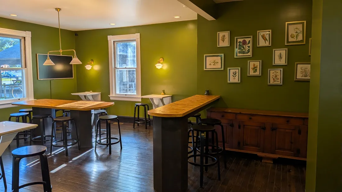 Communal tables and stools below the botanical print wall